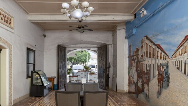 A hallway with a dining area, a chandelier, and a mural of a street scene. - Metro Vigan Inn - Annex (Vigan)