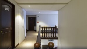 A hallway with a wooden door labeled 204, a staircase with a wooden railing, and a wall with a door labeled 202. - Metro Vigan Inn - Annex (Vigan)