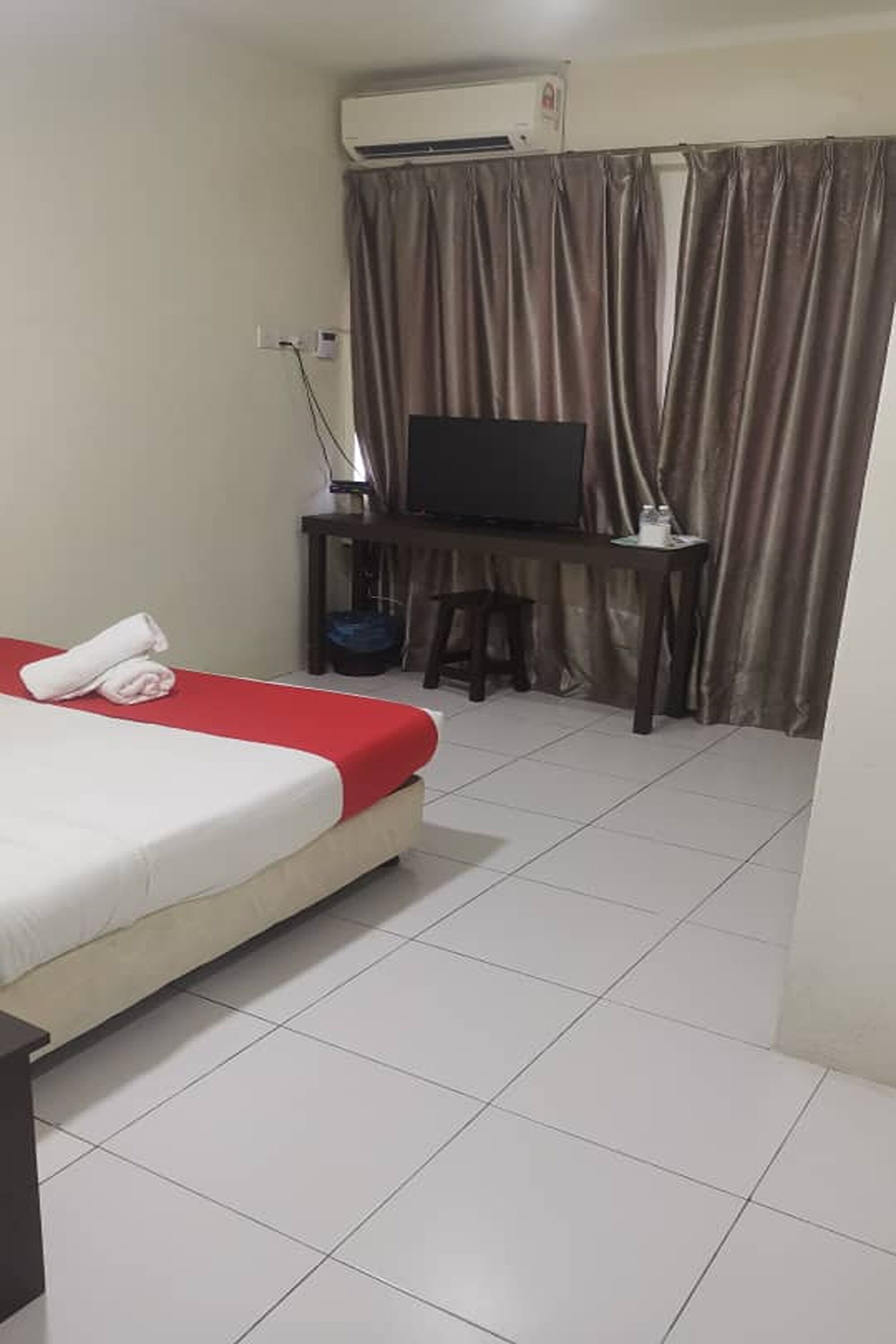 Una habitación de hotel con cama, escritorio, televisor y cortina.