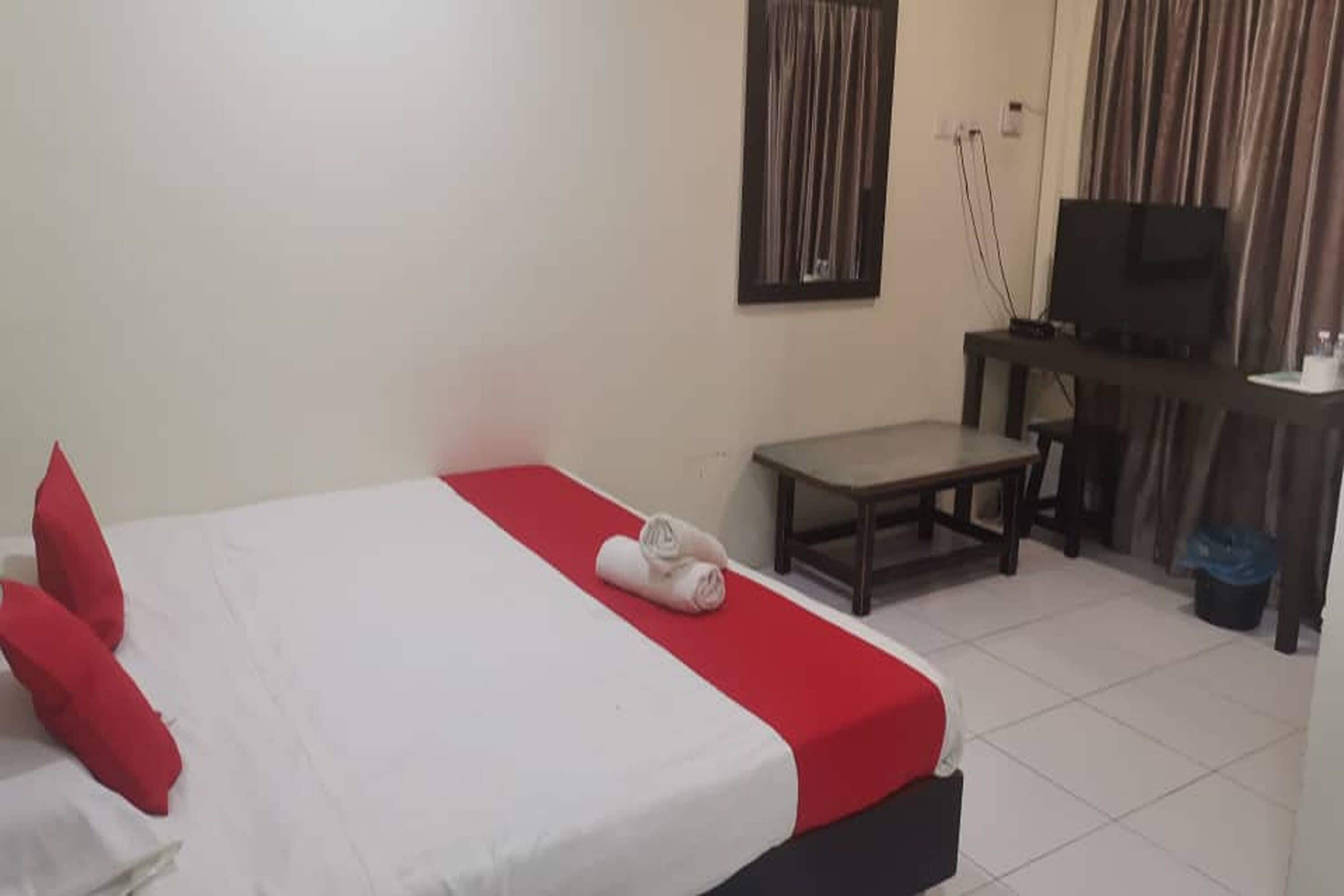 Una camera d'albergo con un letto, un tavolino, una televisione e una tenda.