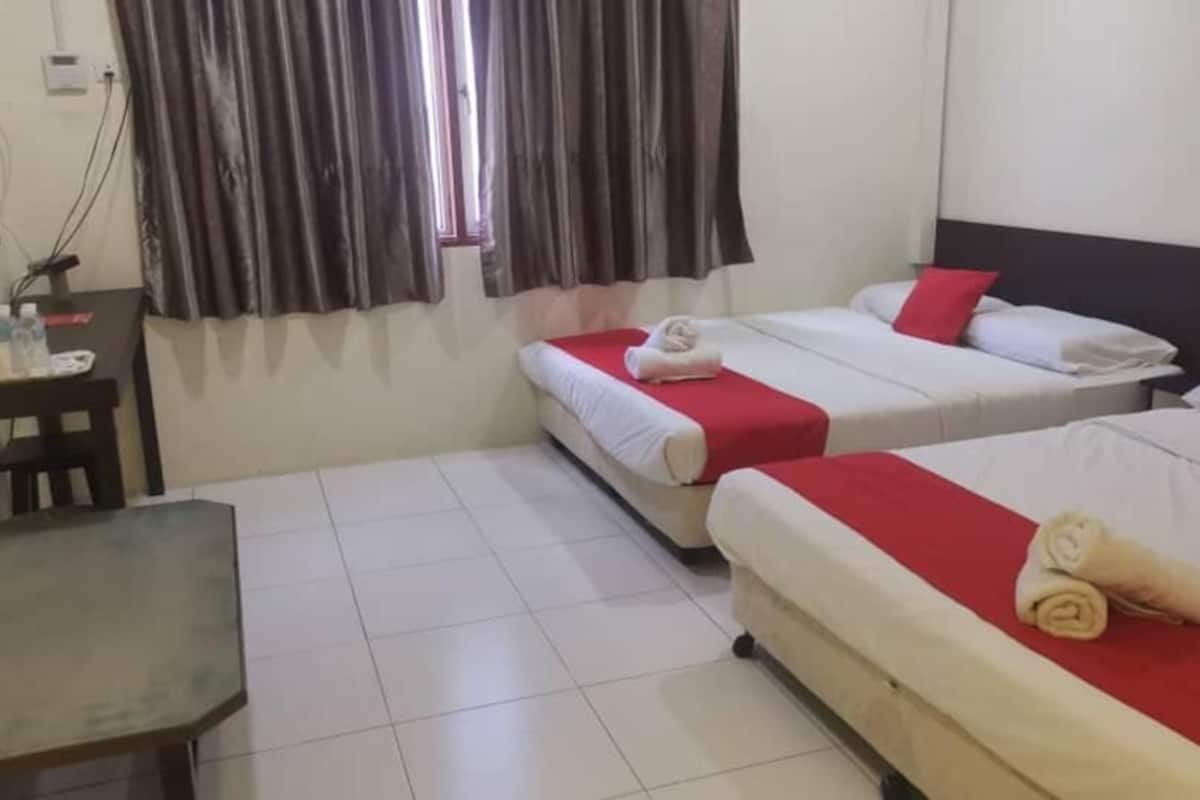 A hotel room with two beds, a desk, a television, and a window with curtains.