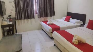 A hotel room with two beds, a desk, and a television.