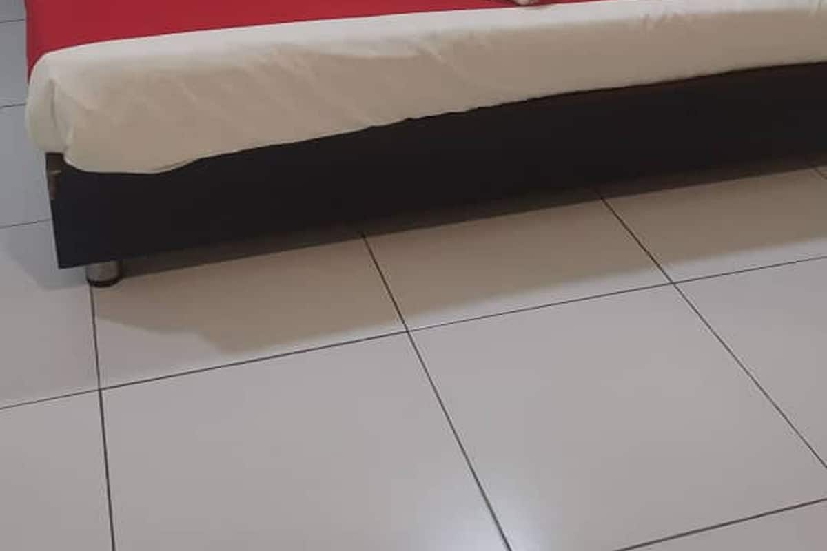 A bed with a red and white bedspread, two red pillows, and a rolled white towel on the bed.
