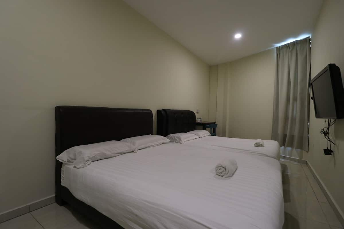 Habitación de hotel con una cama grande, un televisor de pantalla plana en la pared y una mesita de noche con lámpara.