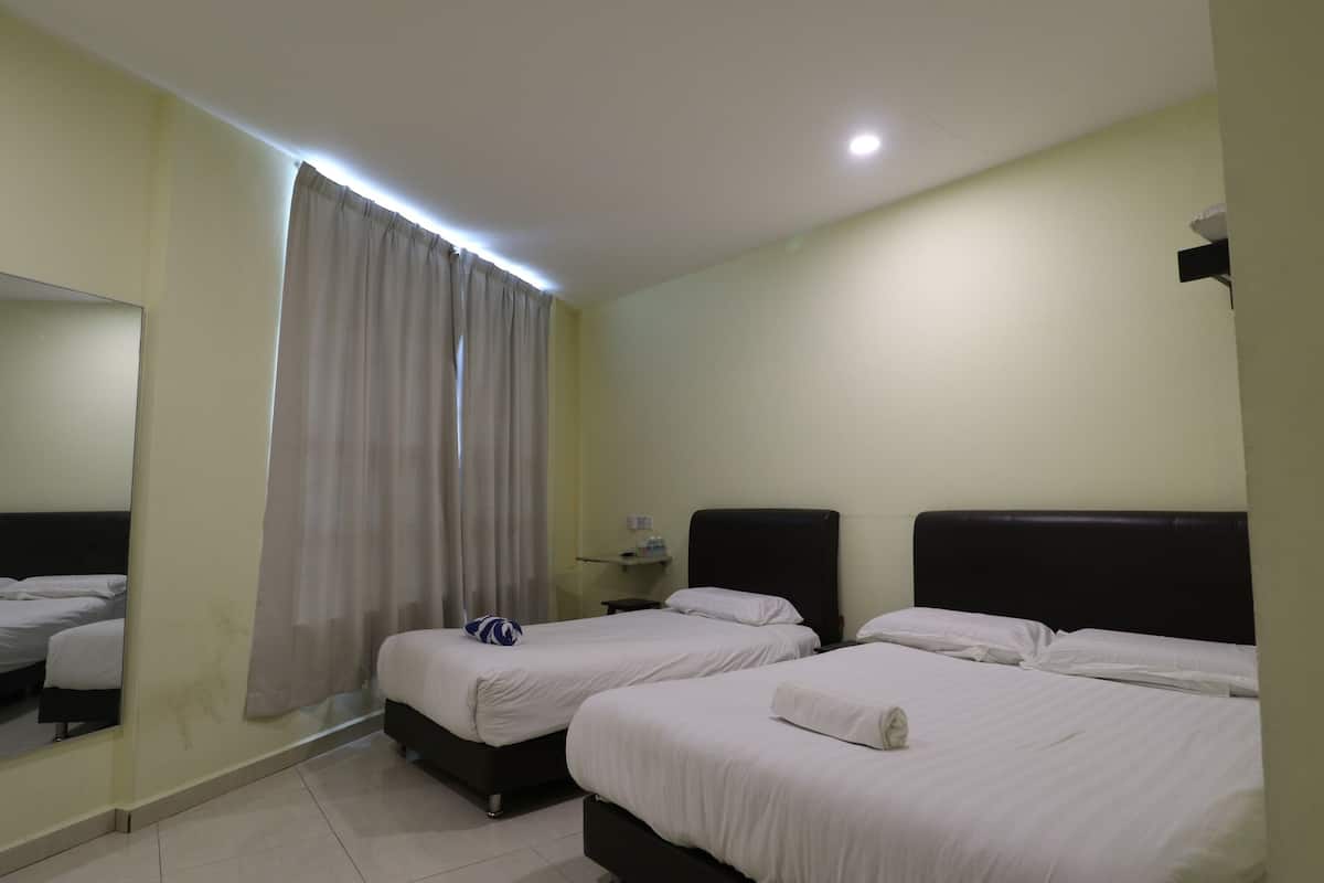 Habitación de hotel con dos camas, un espejo, una ventana con cortinas y una mesita con una lámpara.