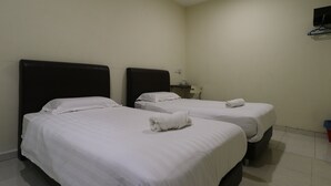 A hotel room with two beds, each with white linens and a rolled towel on the bed.