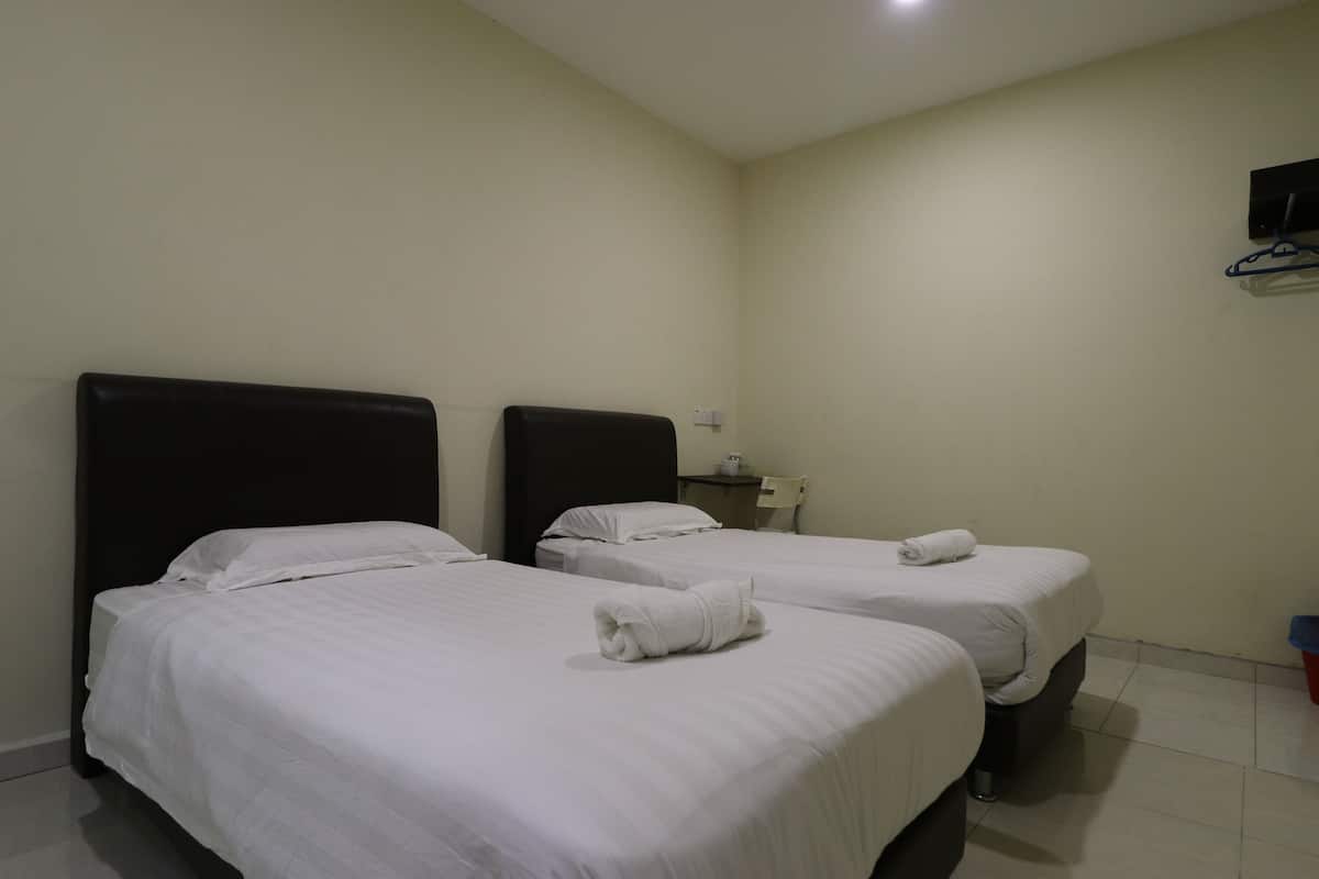 Una habitación de hotel con dos camas, cada una con sábanas blancas y una toalla enrollada sobre la cama.