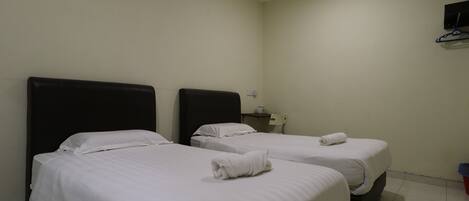 Una habitación de hotel con dos camas, cada una con sábanas blancas y una toalla enrollada sobre la cama.
