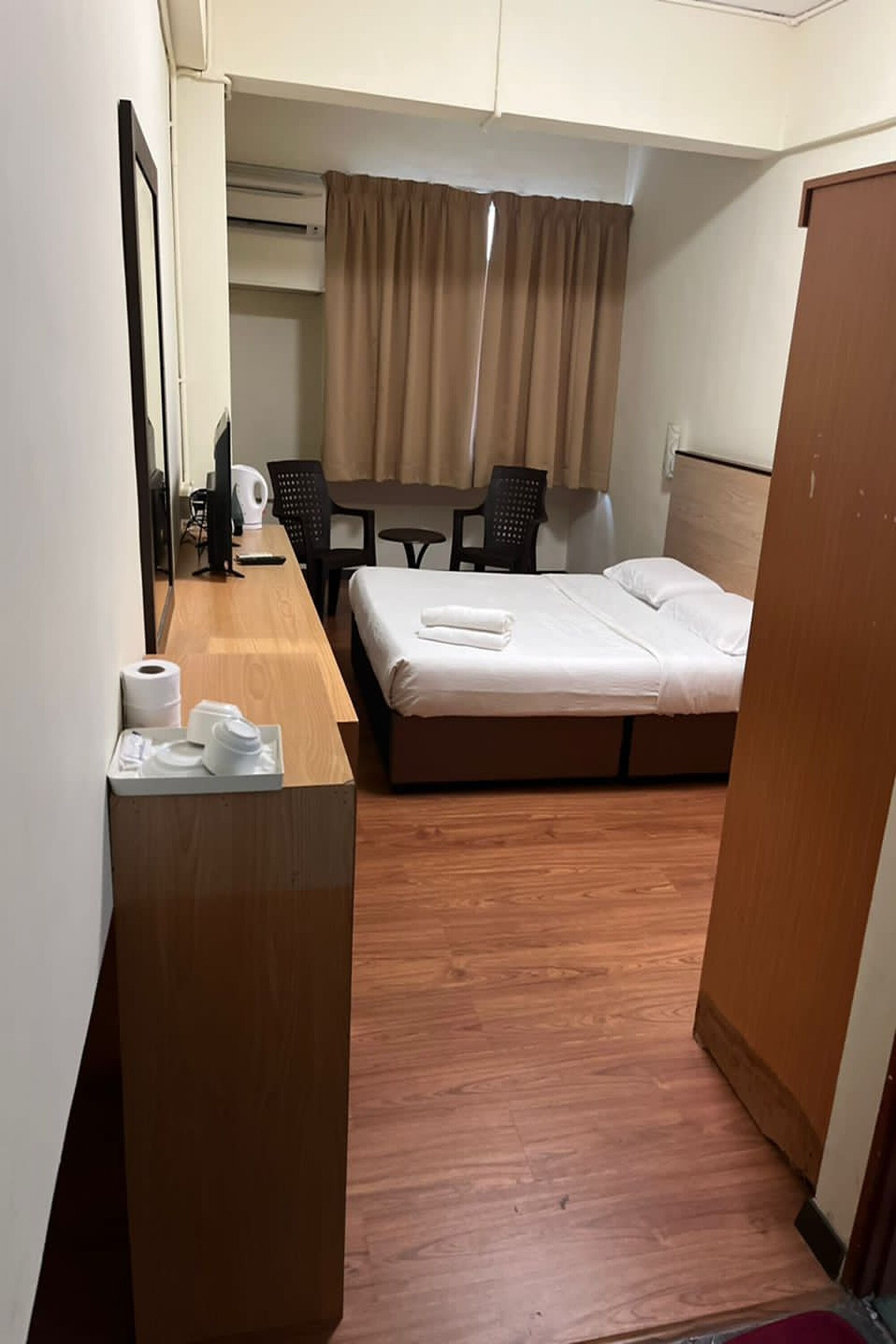 Una habitación de hotel con cama, escritorio, silla, una mesita y un espejo.