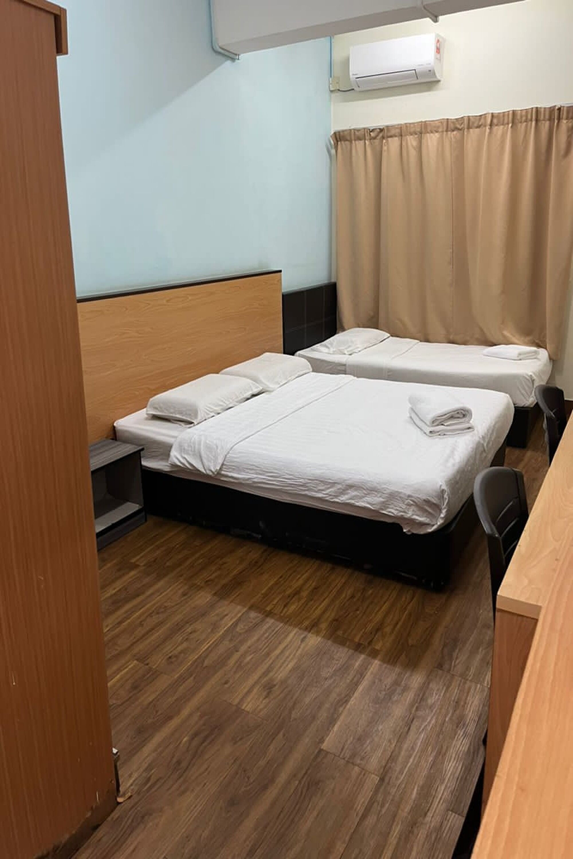 A room with two beds, a wooden headboard, a desk, and a chair.