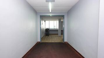 A hallway with a carpeted floor, white walls, and a ceiling light.