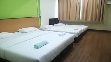 Habitación de hotel con dos camas individuales, una pared verde, una ventana con cortinas color beige y suelo de madera.