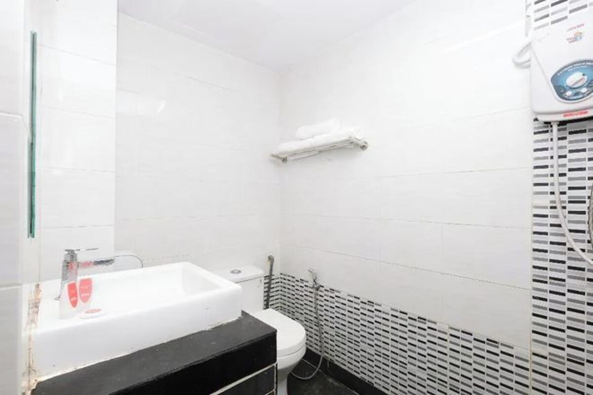 Un baño pequeño con lavamanos, inodoro y toallero blancos.