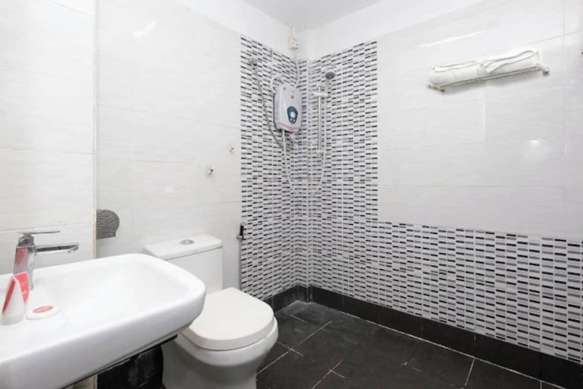 Un baño con lavamanos, inodoro y zona de ducha blancos.