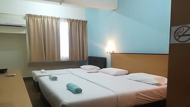 Una habitación de hotel con cama, escritorio y ventana con cortinas.