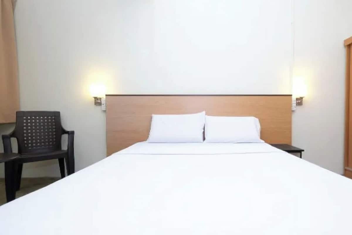 Una habitación de hotel con cama, una silla y un armario.