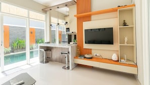A modern kitchen with a large island, bar stools, and a built-in TV. - Kamboja Villa By Zuzu (Kerobokan)