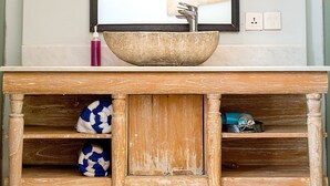 A bathroom with a wooden vanity, a large mirror, and two wall-mounted lights.