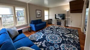A living room with a blue sofa, a patterned rug, and a television on a wooden stand. - Harbor Kee Peaceful Escape By The Bay (Bodega Bay)