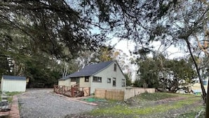 A single-story house with a sloped roof, surrounded by a wooden fence and a gravel driveway. - Harbor Kee Peaceful Escape By The Bay (Bodega Bay)