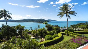 Un complexe hôtelier tropical offrant une vue sur l’océan et les montagnes, doté de jardins aménagés avec soin et d’un espace piscine.