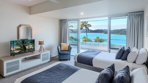 Une chambre d’hôtel avec deux lits, une télévision, une chaise et un balcon donnant sur la mer.