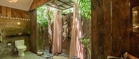 A bathroom with a wooden interior, a toilet, a sink, and a shower area with curtains.
