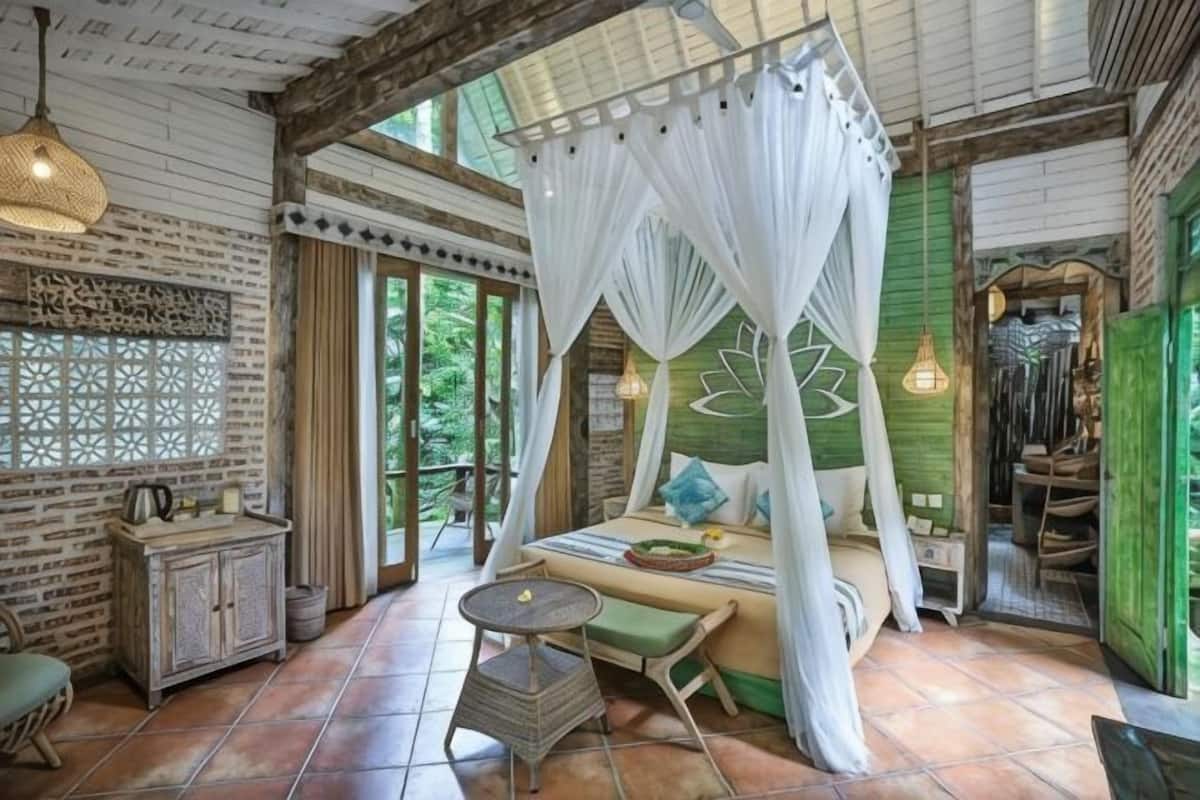 Une chambre avec un lit à baldaquin, une petite table, un banc rembourré et un mur décoratif.