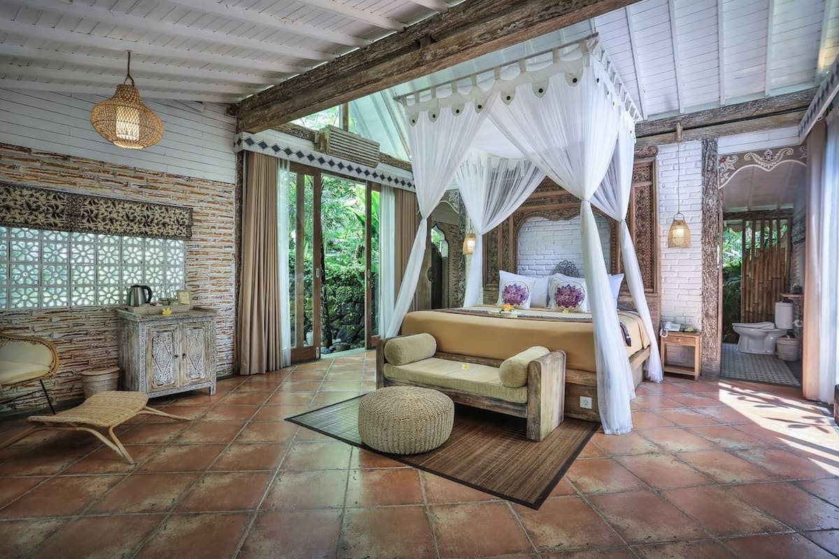 Une chambre spacieuse avec un grand lit, un coin salon et une vue sur l’extérieur.