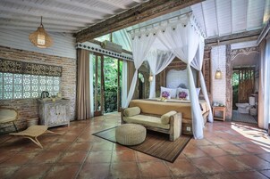 Un dormitorio amplio con una cama grande, una zona de estar y vistas al exterior.