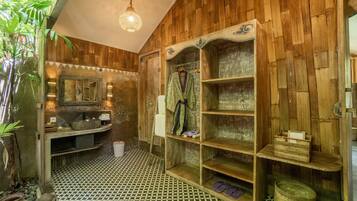 A bathroom with wooden walls, a patterned floor, a sink, a mirror, shelves, and a hanging robe.