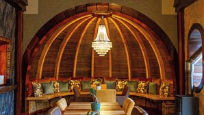 A dining area with a wooden bench seating, a chandelier, and a fireplace. - Mont Eco Game Reserve (Montagu)