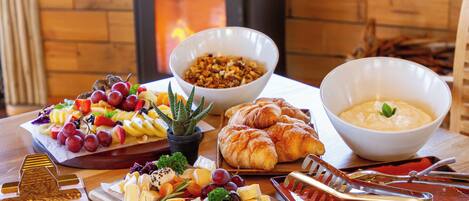 Un bufé de desayuno con varios quesos, frutas y productos de pastelería.