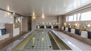 A modern bathroom with a central pool, multiple sinks with mirrors, and a tiled floor.