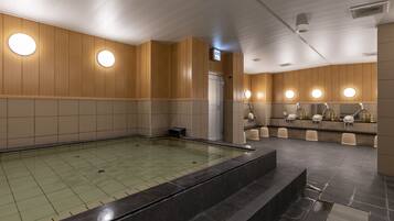 Uma piscina interior moderna, com piso ladrilhado, painéis de madeira e iluminação circular.