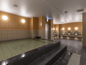 Een modern binnenzwembad met betegelde vloer, houten wandpanelen en ronde verlichtingsarmaturen.