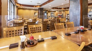 A restaurant with wooden tables and chairs, a coffee machine, and a menu stand.