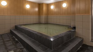 A modern indoor swimming pool with wooden panel walls and circular wall lights.