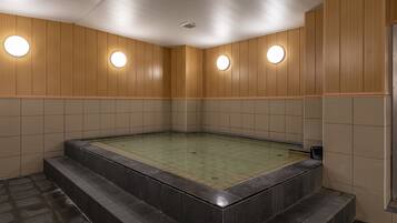 Piscina interior moderna com painéis de madeira e luminárias circulares nas paredes.