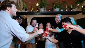 A group of people toasting with drinks in a room with a bar area and decorative plants. - Mad Monkey Dumaguete (Dumaguete)