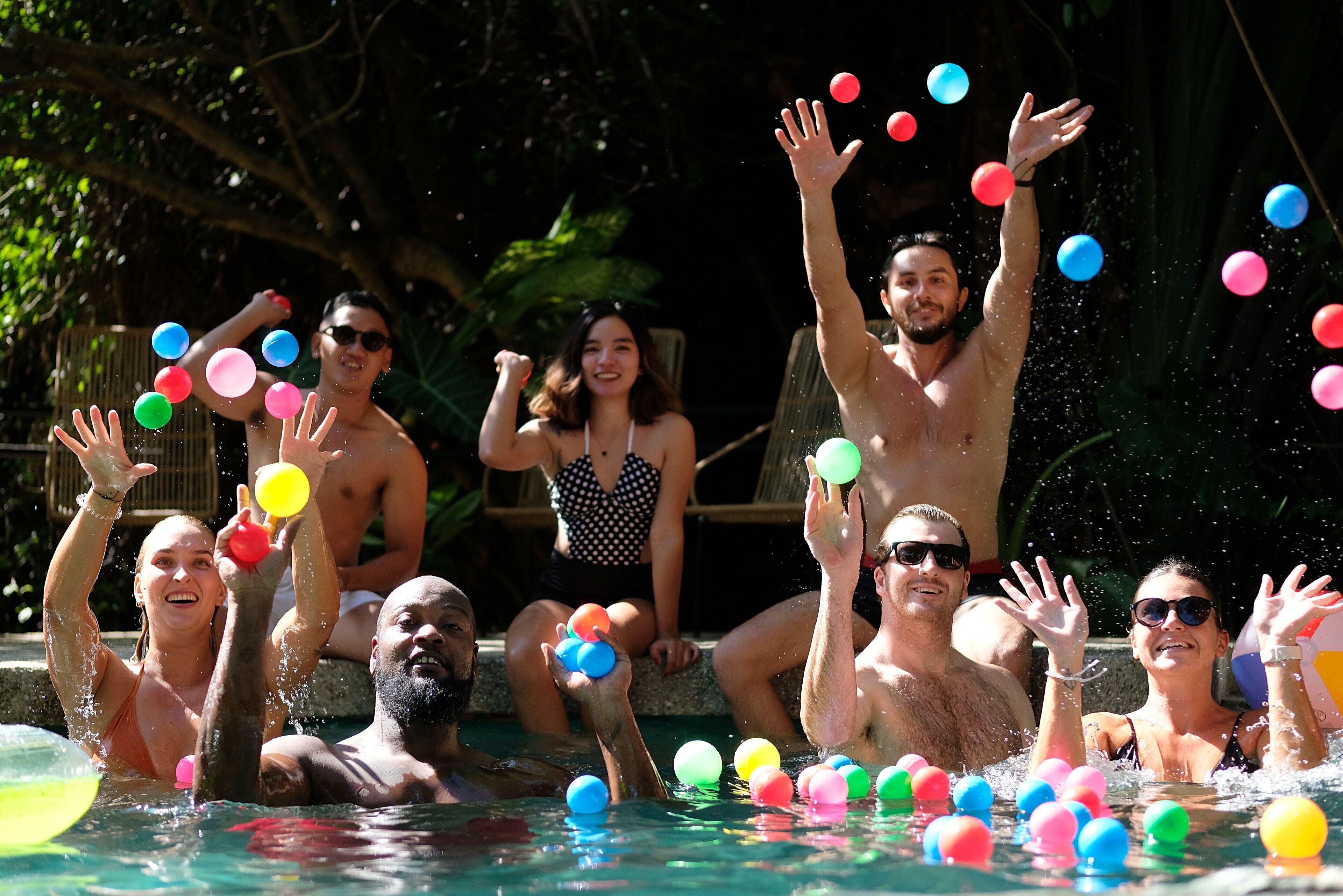 Un groupe de personnes dans une piscine, avec des balles colorées flottant autour d’elles.