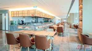 Un restaurante moderno con una barra larga, zona de estar y cocina al fondo.