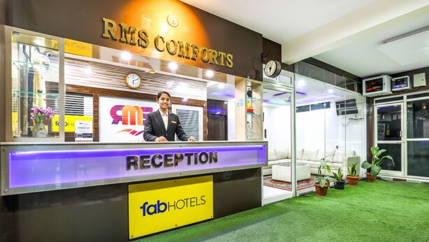 Ein Empfangsschalter mit einer Uhr, einem Schild mit der Aufschrift 'RMS COMFORTS' und einem Schild von 'fabHOTELS'.