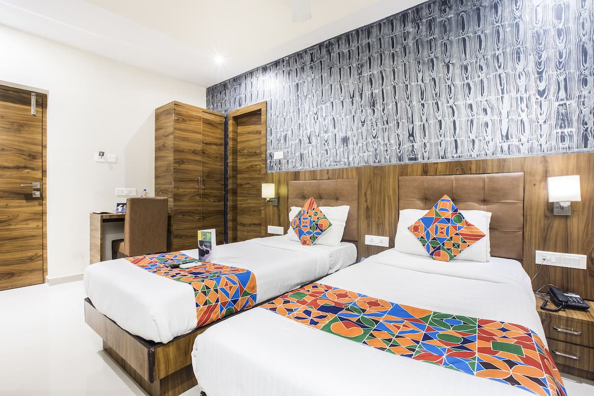 A hotel room with two beds, wooden headboards, and a patterned wall.