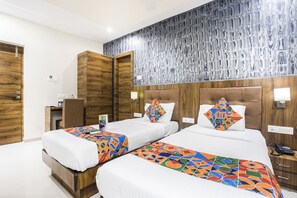 A hotel room with two beds, wooden headboards, and a patterned wall. - Fabhotel Amour (Mumbai)