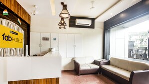 A hotel reception area with a reception desk, a sofa, a couch, and a large window providing a view of the outside. - Fabhotel Amour (Mumbai)