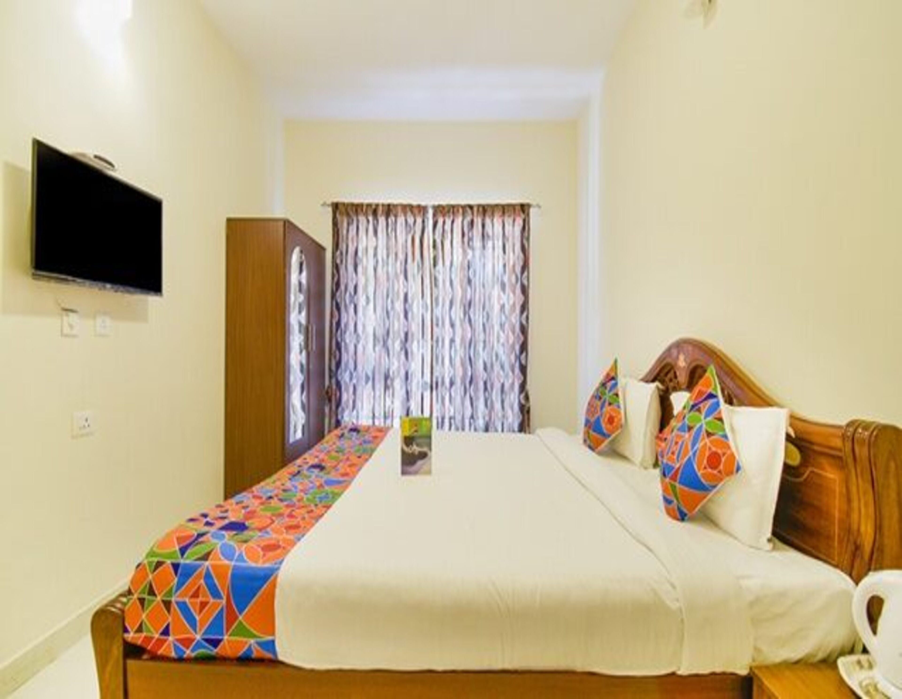 A hotel room with a bed, a television, a wardrobe, and a curtain.