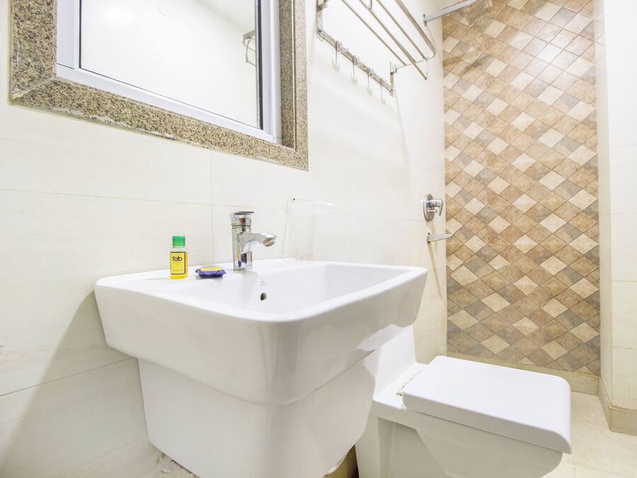A bathroom with a white sink, toilet, and a mirror with a decorative frame.