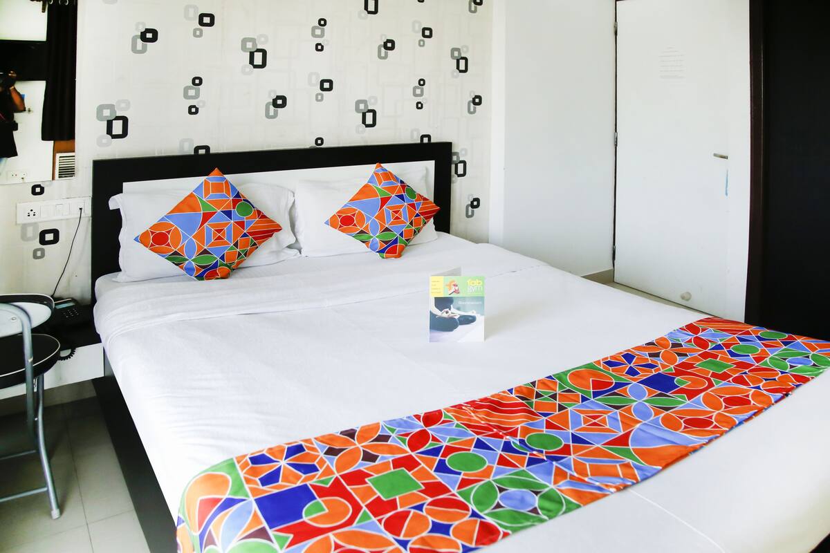 A hotel room with a bed, a desk, and a chair.