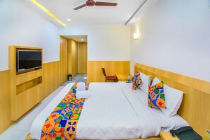 Habitación de hotel con una cama grande, un televisor montado en la pared, un escritorio y una silla.